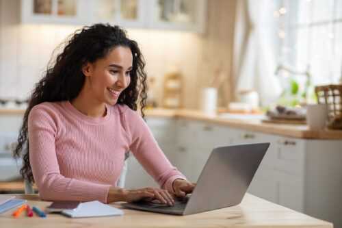 A woman at a desk working on a laptop and smiling on Skill Developers' website
